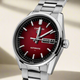 Carrera watch with red face and silver bracelet on a beige background. Gent's TAG Heuer Carrera Automatic Watch. The 41mm case. Five year TAG Heuer warranty. model WDA2113.BA0043