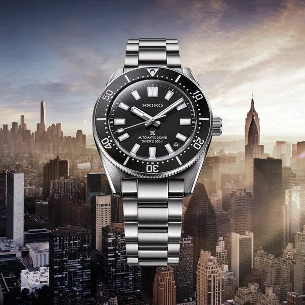 Gent's Seiko Prospex 1965 Heritage Divers 300m Automatic Watch. The 40mm case and bracelet are stainless steel. The bezel and dial are black. The glass is sapphire crystal. The watch has a date function and is 300m water resistant. The movement is automatic
