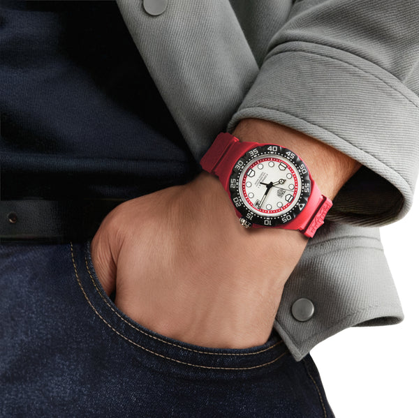 Person wearing a watch with a red strap and black and white face.