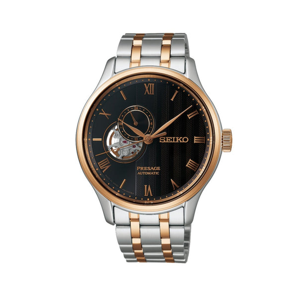 Seiko watch with two-tone metal strap on gray backgroundGents Seiko Presage Japanese Garden Automatic Watch. The 41.8mm case and bracelet are bicolour: rose gold PVD and stainless steel. The dial is black with a textured pattern, rose coloured roman numerals and hands, 24-hour indicator sub-dial and circular shaped movement window. The watch has a sapphire crystal glass with a see-through case back. The movement is automatic. MODEL SSA466J