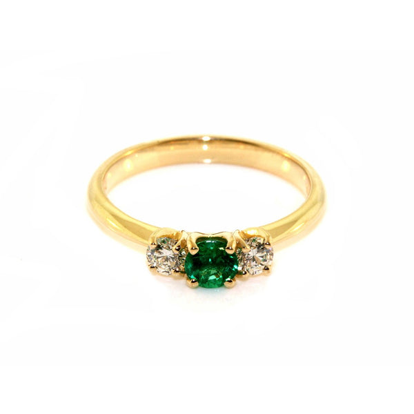 Handfinished 18k Yellow Gold Emerald and Diamond Three Stone Ring.&nbsp;The ring is set with a0.32ct Round Natural Emerald Bright Green in Colour, measuring 4.4mm and 0.60ct Round Brilliant Cut diamonds The emerald and diamonds are set inline into U shaped four claw settings. &nbsp;The shank is slightly raised at the shoulder and has a rounded profile. Based on the stock finger size N, the ring weighs 3.2 grams. FG Colour, VS2-Sl1 Clarity.