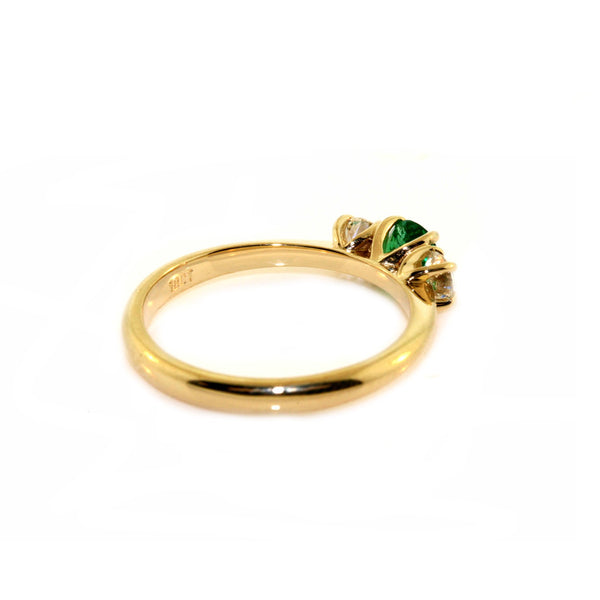 Handfinished 18k Yellow Gold Emerald and Diamond Three Stone Ring.&nbsp;The ring is set with a0.32ct Round Natural Emerald Bright Green in Colour, measuring 4.4mm and 0.60ct Round Brilliant Cut diamonds;The emerald and diamonds are set inline into U shaped four claw settings. &nbsp;The shank is slightly raised at the shoulder and has a rounded profile. &nbsp;Based on the stock finger size N, the ring weighs 3.2 grams. FG Colour, VS2-Sl1 Clarity.