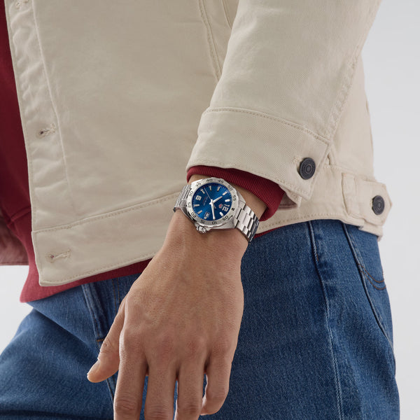 Person wearing a blue watch on a neutral background