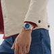 Person wearing a blue watch on a neutral background