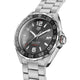 A silver stainless steel wristwatch with a dark gray dial, featuring a black rotating bezel with white markings, silver-tone hour markers, and a date window at 3 o'clock. The watch is shown at a three-quarter angle against a solid black background, with the brand name 'TAG HEUER' visible on the dial.