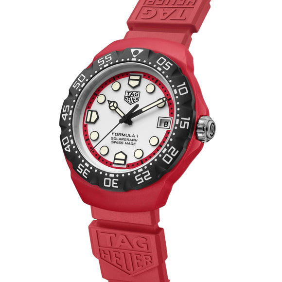 A red rubber strap watch with a black bezel and white dial, featuring the TAG Heuer logo on the strap and watch face, set against a solid black background.