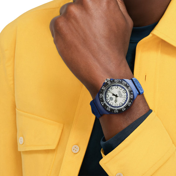 Person wearing a blue watch with a white face on a yellow shirt background